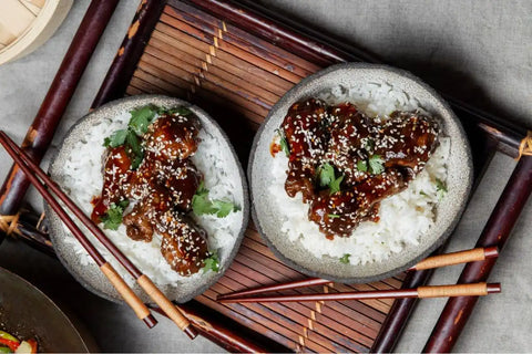 Olahan daging dengan saus coklat di atasnya dan taburan wijen