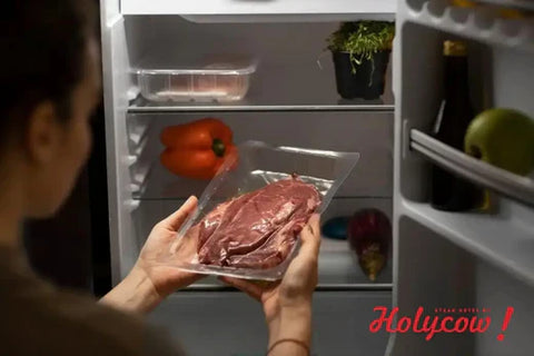 Perempuan memegang daging di depan kulkas