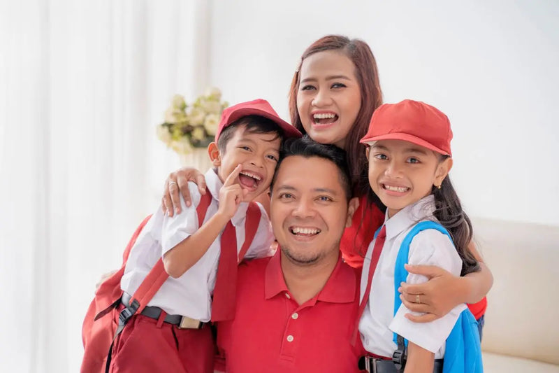 Keluarga bahagia berfoto bersama dengan anak-anak memakai seragam sekolah