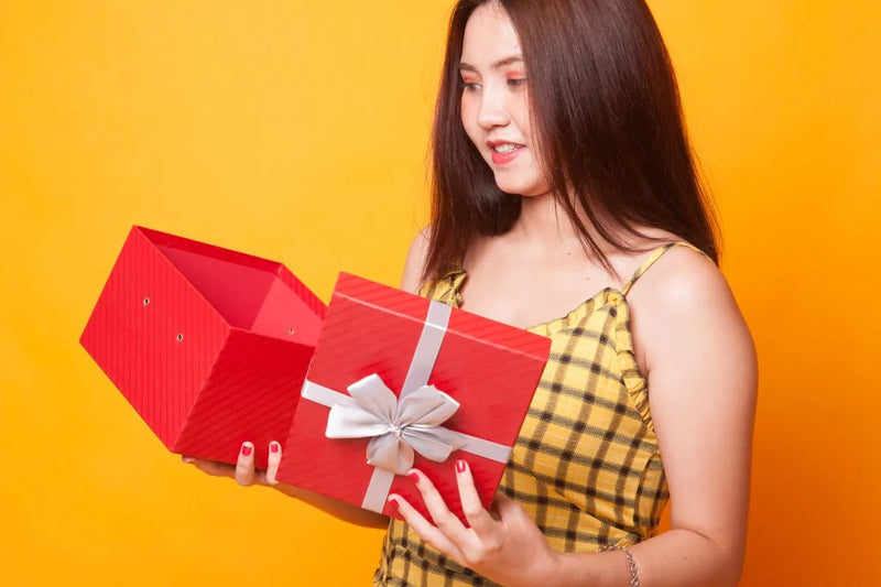 Wanita membuka kotak hadiah merah berisi kejutan