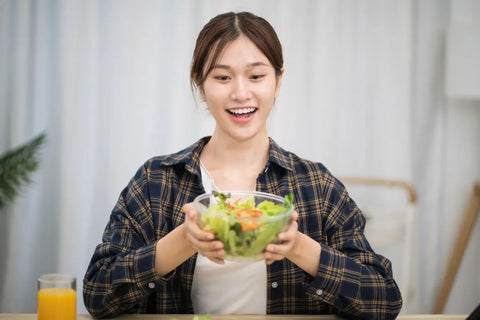 Wanita tersenyum memegang mangkuk salad sayuran segar