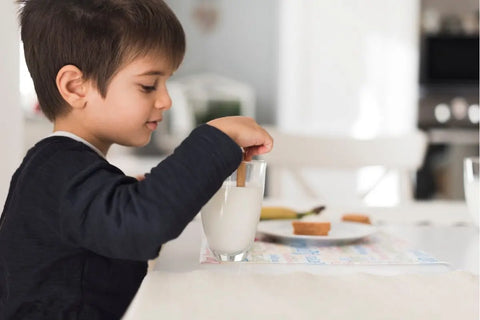 Anak mencelupkan biskuit ke susu
