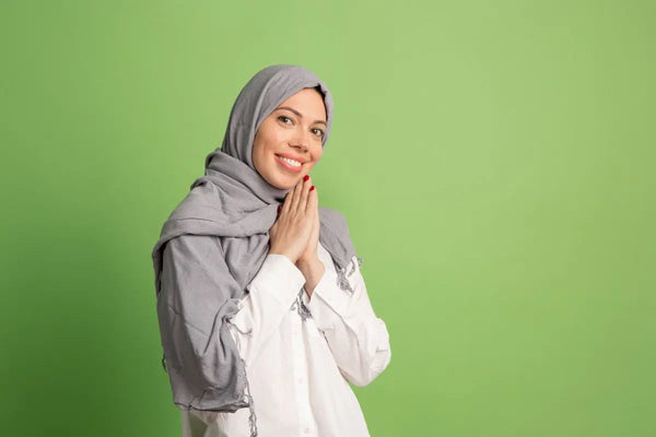 wanita berhijab sedang berpose mengucapkan selamat di background warna hijau