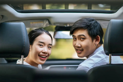 pasangan yang menengok dari dalam mobil sambil tersenyum