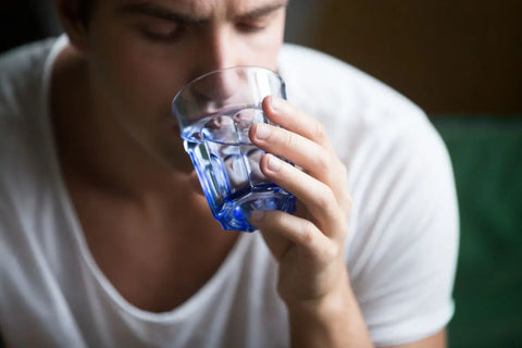 orang yang sedang minum air karena dehidrasi