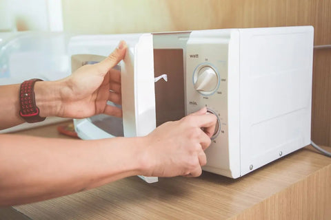 Seseorang membuka pintu oven microwave berwarna putih